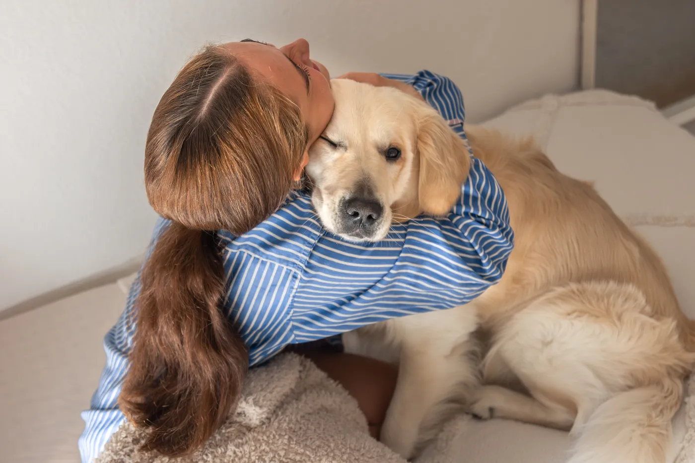 O persoană îmbrățișând un golden retriever pe canapea